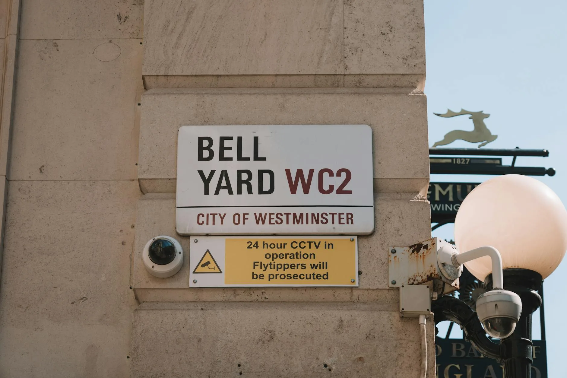 CCTV warning sign on a street with a dome camera visible