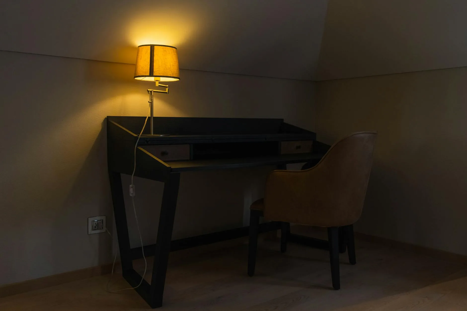 Desk lamp glowing with warm light in a dimmed evening room