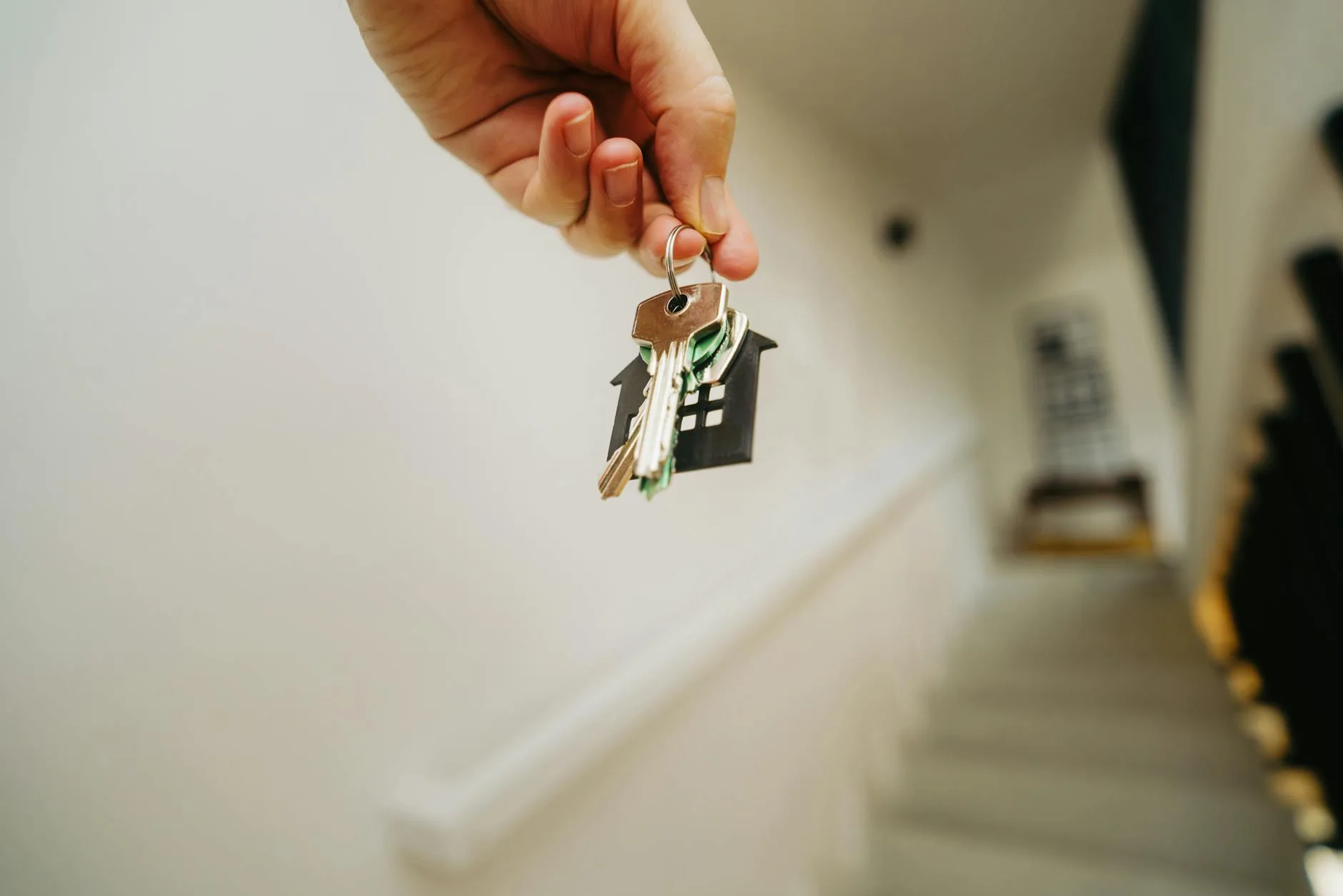 Hand holding a house key outside a front door